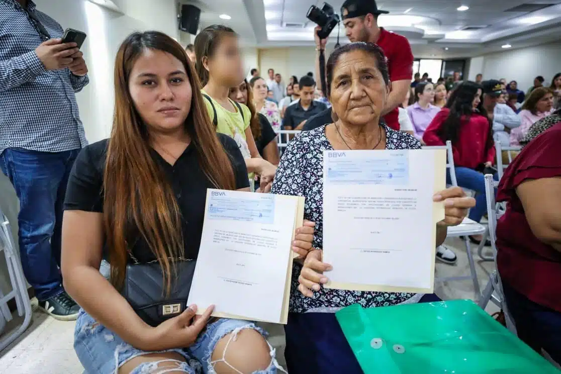 Mujeres con su cheque por daños de Norma