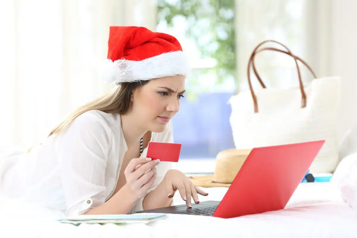 Mujer sosteniendo su tarjeta frente a la pantalla de una laptop