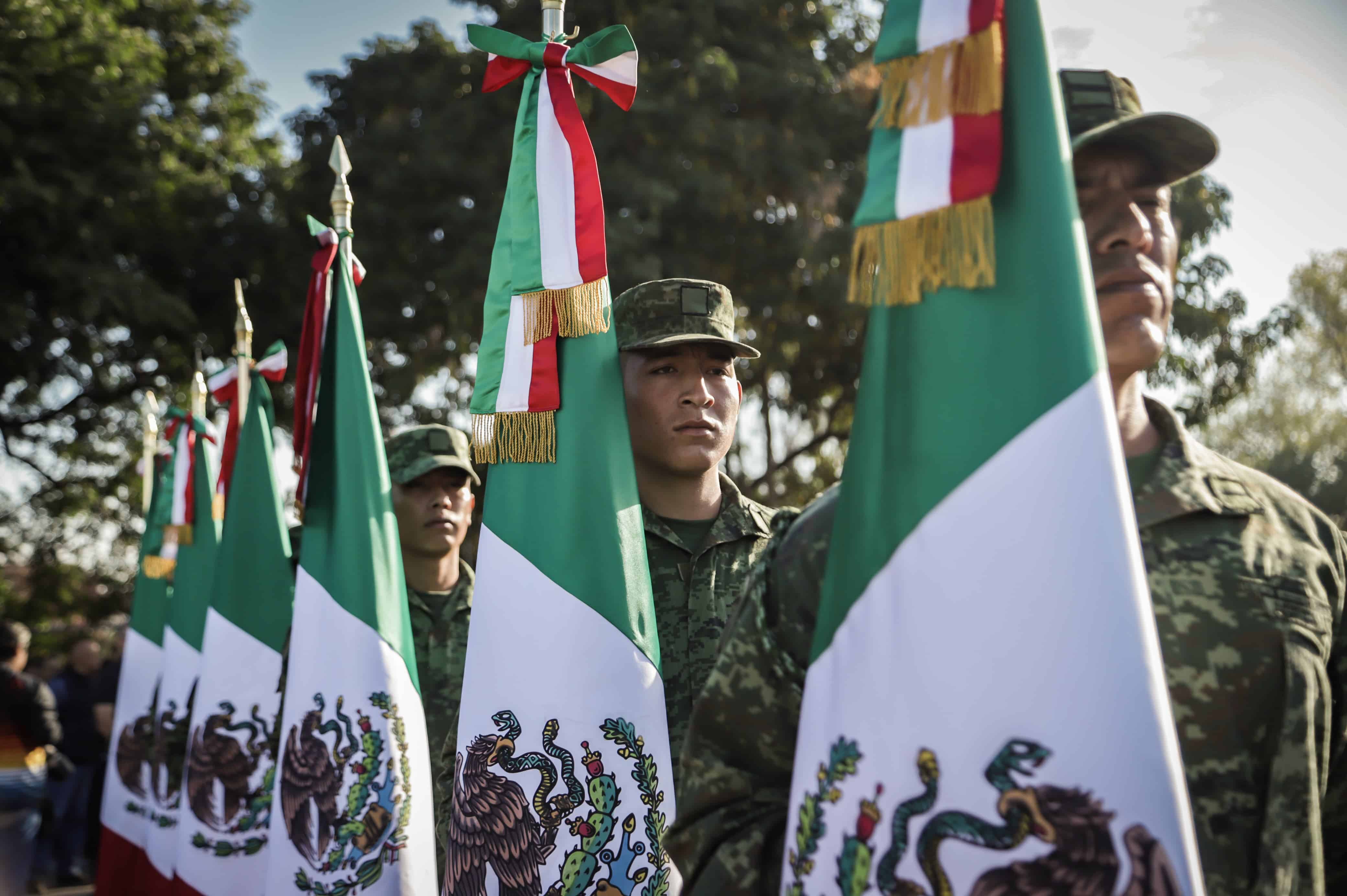 Militares sosteniendo la bandera de México