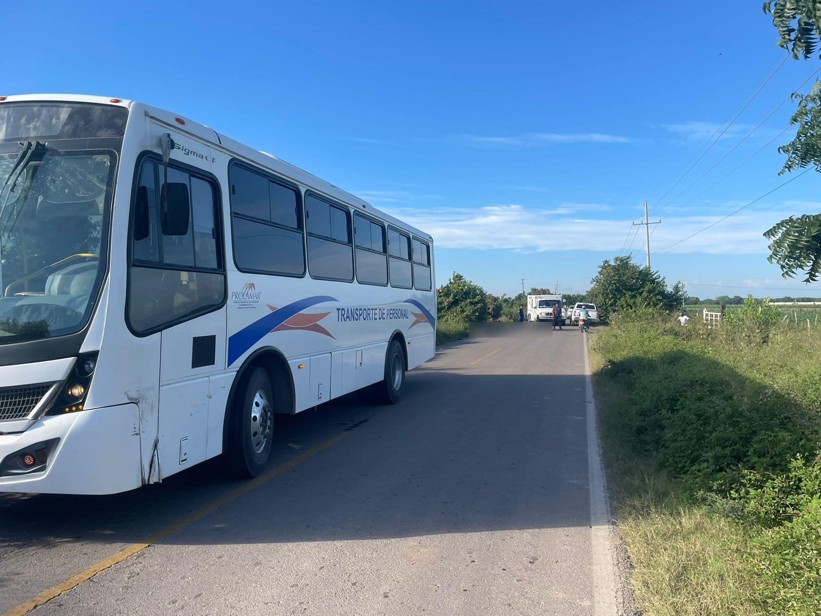 Camión de pasajeros estacionado en la carretera. Autoridades se encuentran al fondo