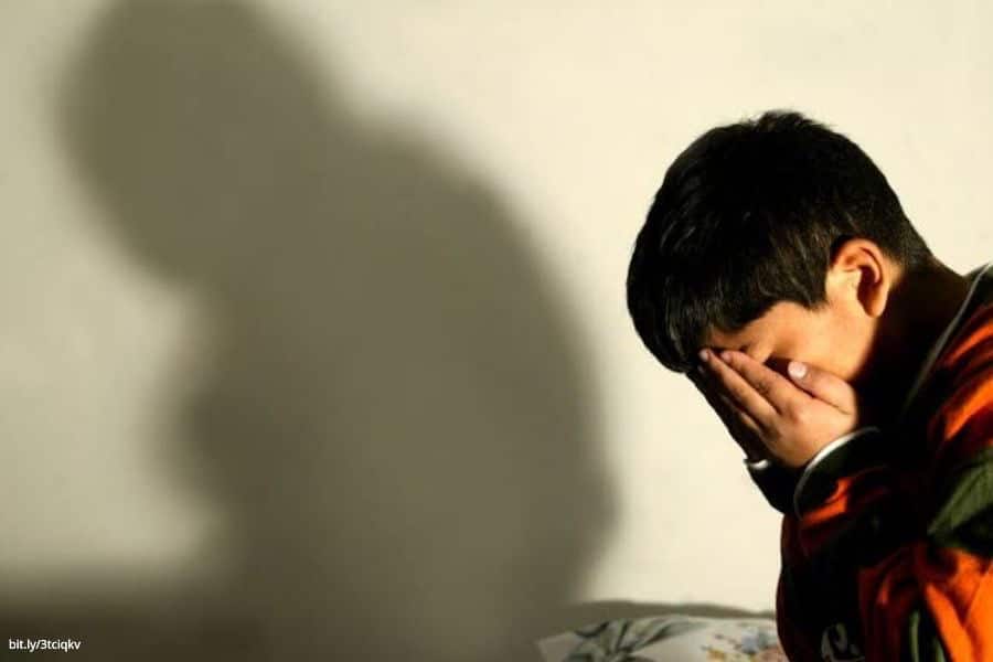 Niño cubriéndose el rostro con sus manos.