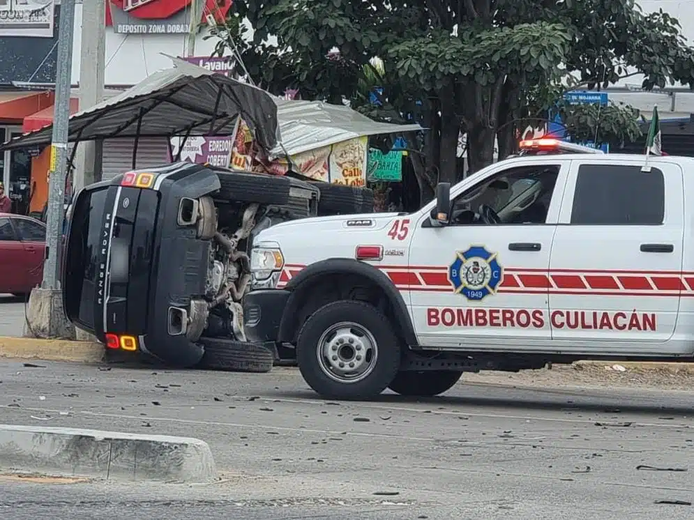 Bomberos en el lugar de un accidente tipo choque y volcadura, y una camioneta con los neumáticos hacia un lado en Culiacán