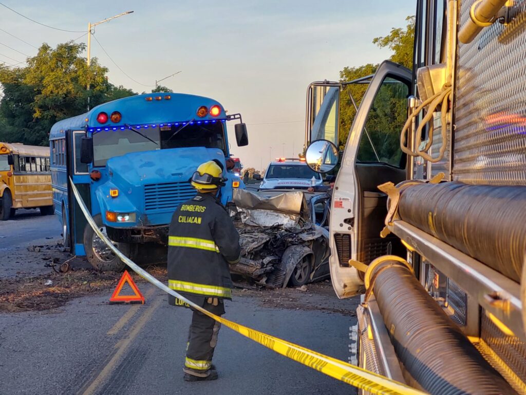 Una persona con uniforme de bomberos en el lugar de un accidente entre un camión agrícola color azul chocado del lado del conductor y un carro destrozado en Costa Rica, Culiacán