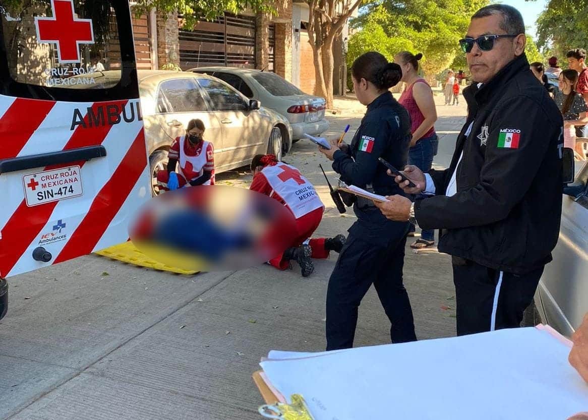 Socorristas de la Cruz Roja atendiendo a una mujer que está sobre el piso tras ser atropellada. A un lado, una ambulancia y policías municipales