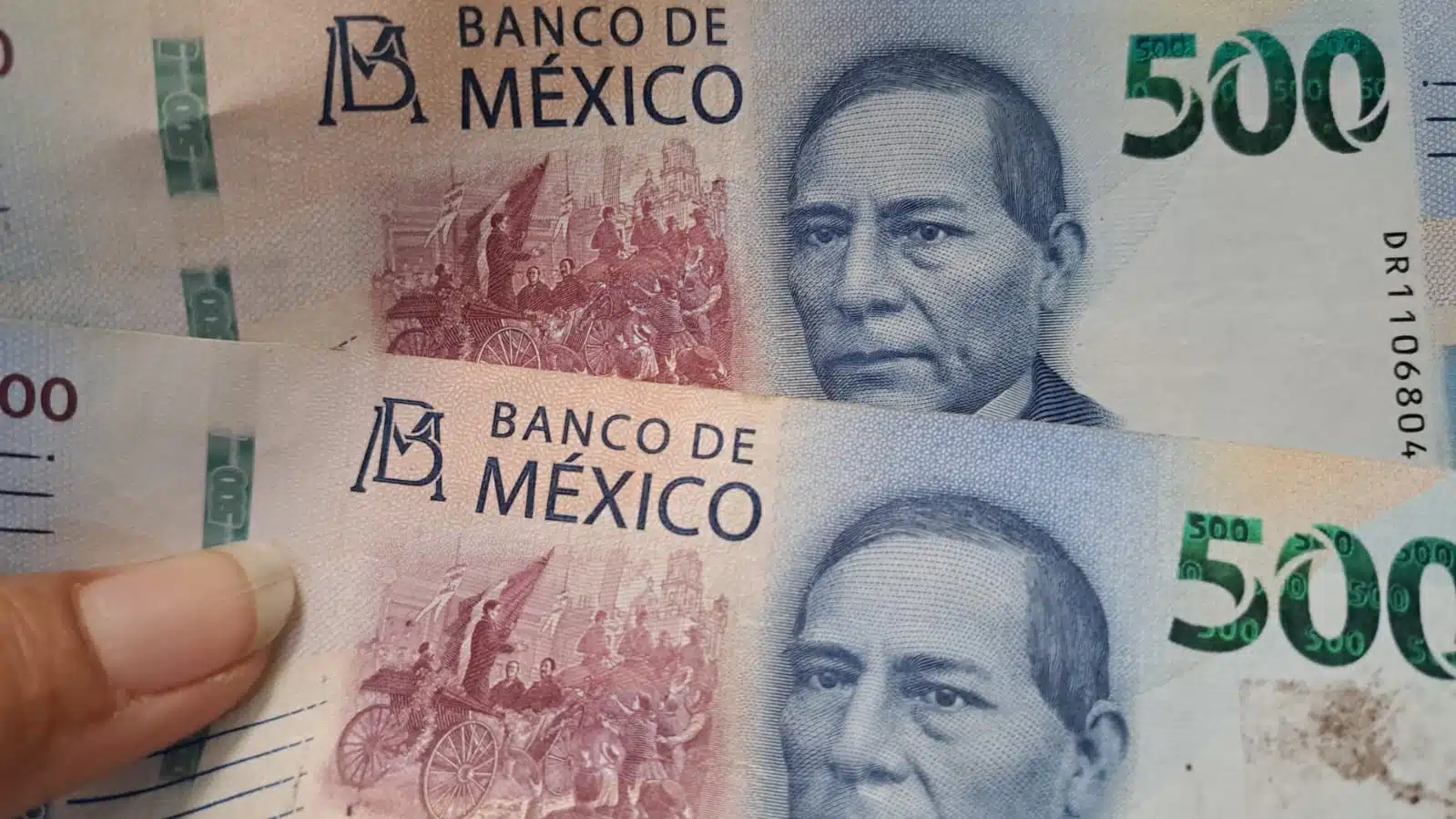 Manos sosteniendo dos billetes de quinientos pesos mexicanos