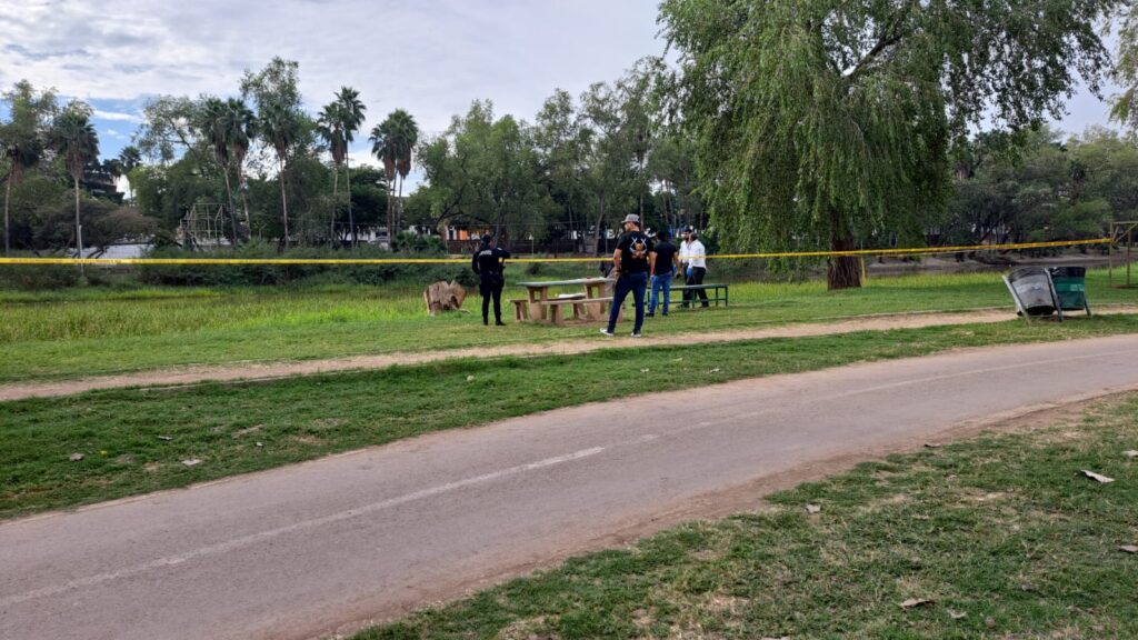 Personas y cinta amarilla delimitando el área de un crimen en el parque Las Riberas en Culiacán