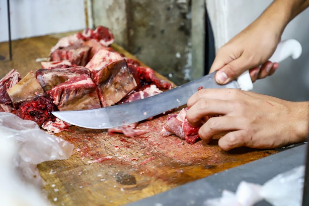 Manos pelando carne de res en comercio de mercado en Culiacán