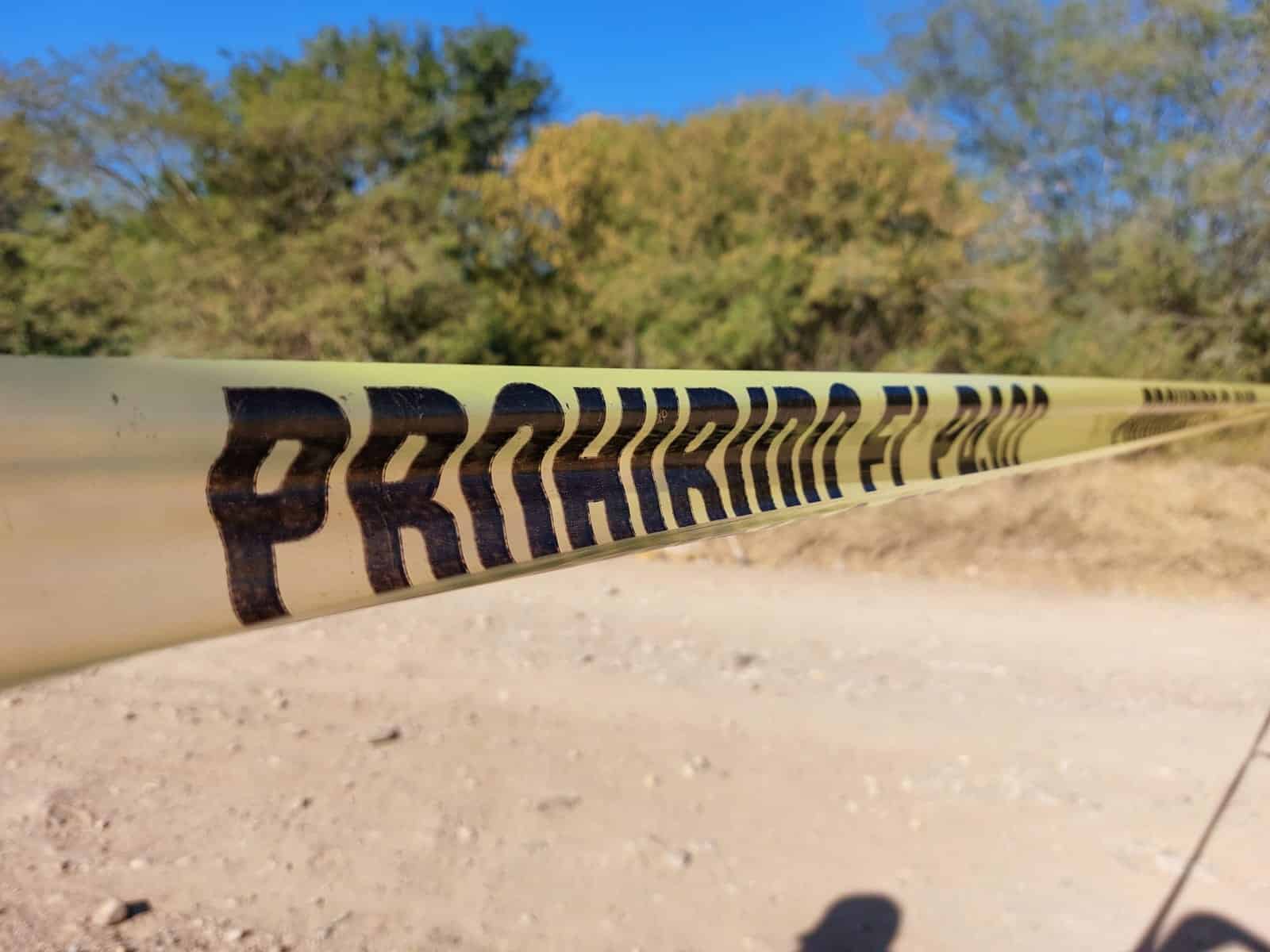 Cinta amarilla de prohibido el paso en zona de hallazgo de un cuerpo sin vida en un camino de terracería en Culiacán