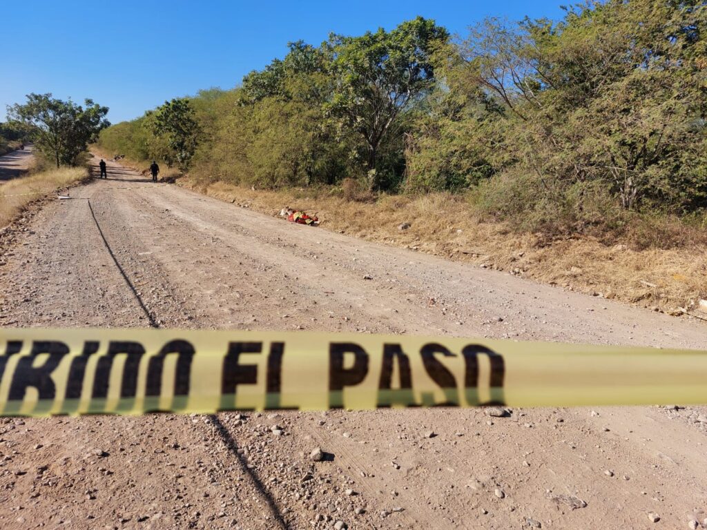 Cinta amarilla de prohibido el paso en zona de hallazgo de un cuerpo sin vida en un camino de terracería en Culiacán