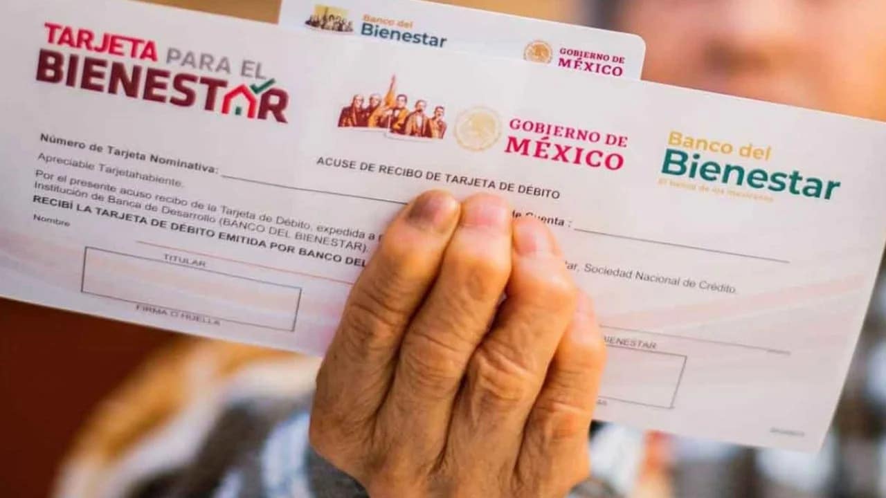 Sobre de una tarjeta de la pensión del Bienestar tomado de la mano de una persona adulta mayor