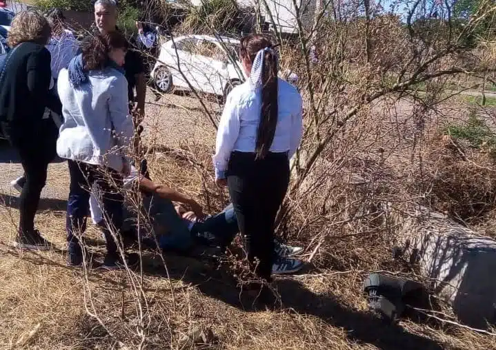 Personas auxiliando a motociclista accidentado.