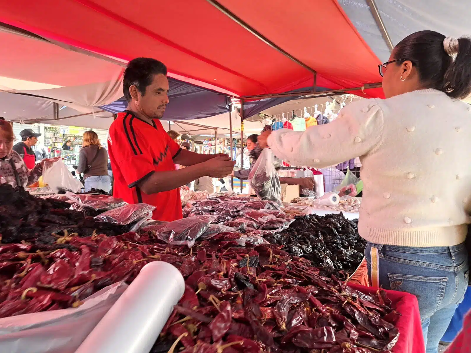 Señora compra carne en un puesto del tianguis dominical en Los Mochis