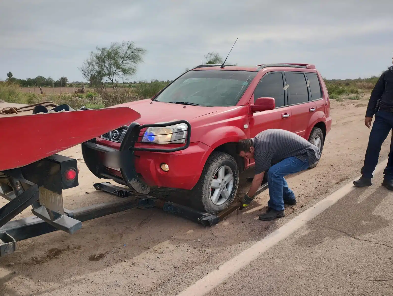 Hombre intenado levantar camioneta de color rojo