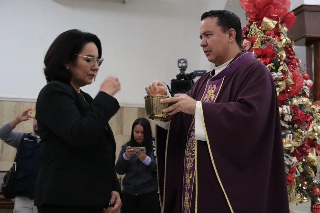 funcionaria de Ahome recibiendo ostia de sacerdote