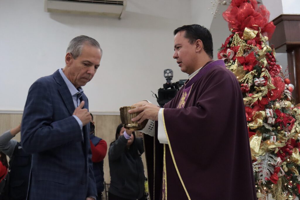 Alcalde de Ahome recibiendo ostia de sacerdote