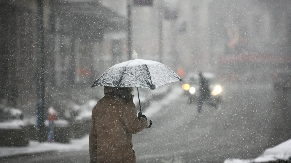 Persona abrigada con paraguas durante nevada
