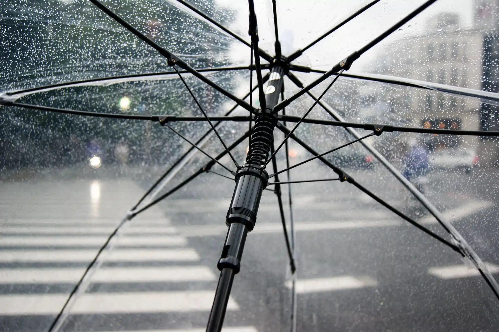 Vista del interior de un paraguas transparente empañado por gotas de lluvia en la ciudad