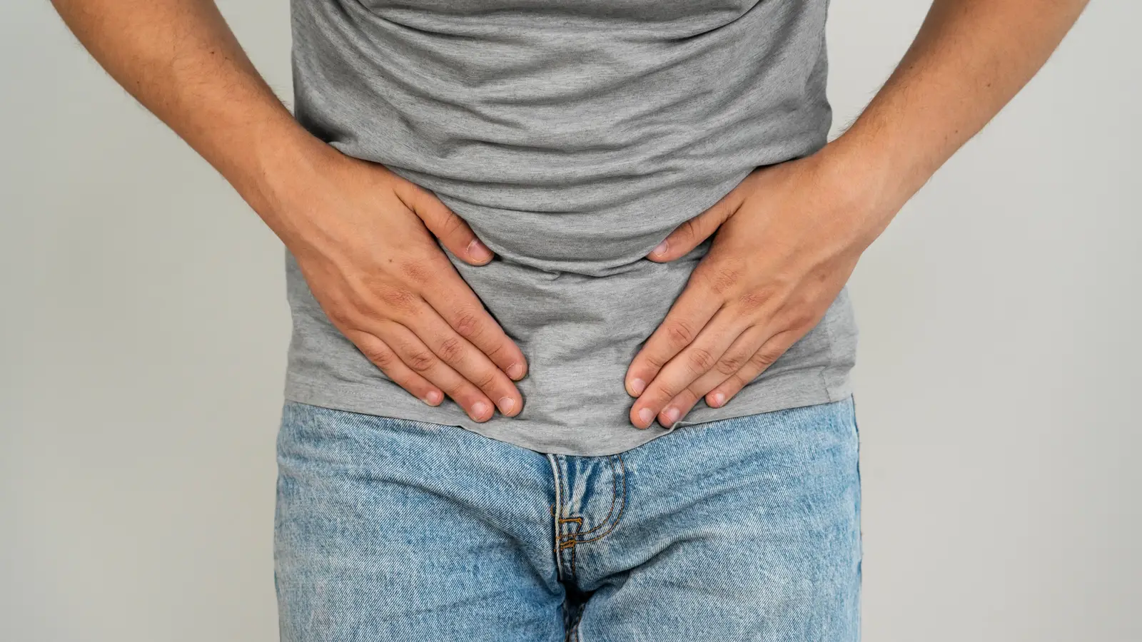 Hombre tocándose el el abdomen bajo por dolor