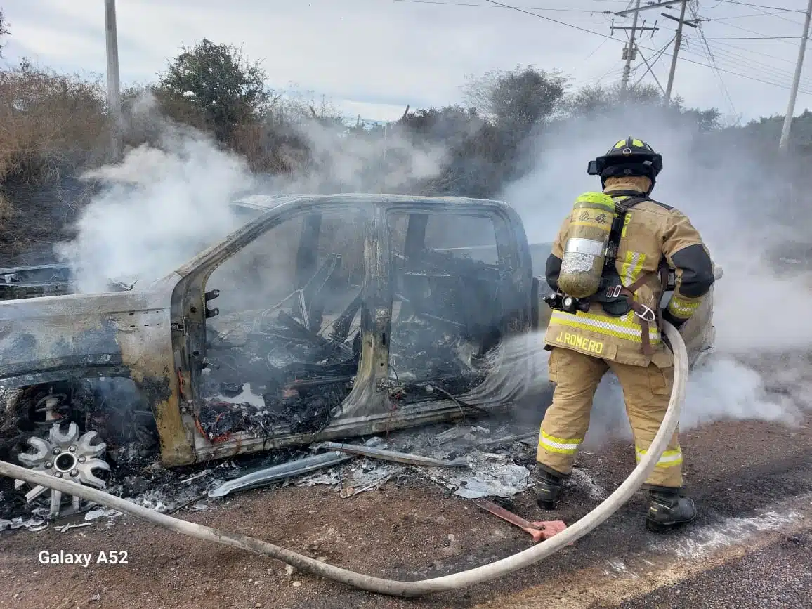 Bomberos atendiendo el incendio de la camioneta