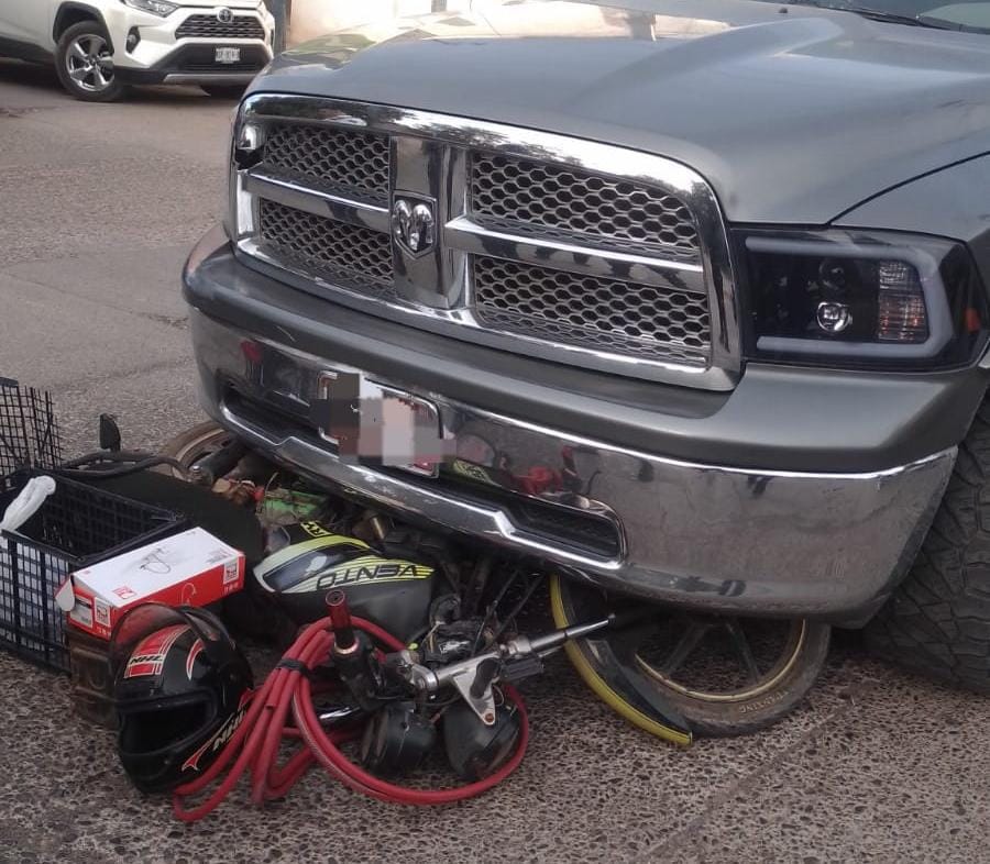 Motocicleta debajo de una camioneta tras accidente