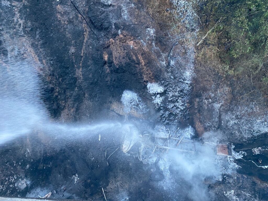 Agua apagando el incendio de una cisterna de un tráiler con gasolina en el fondo de un barranco por la autopista Durango-Mazatlán tras un accidente tipo volcadura