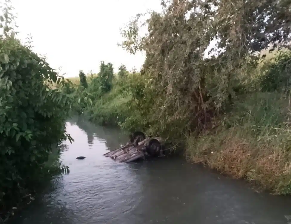 Carro con los neumáticos hacia arriba adentro de un canal con poca agua en Eldorado, Culiacán