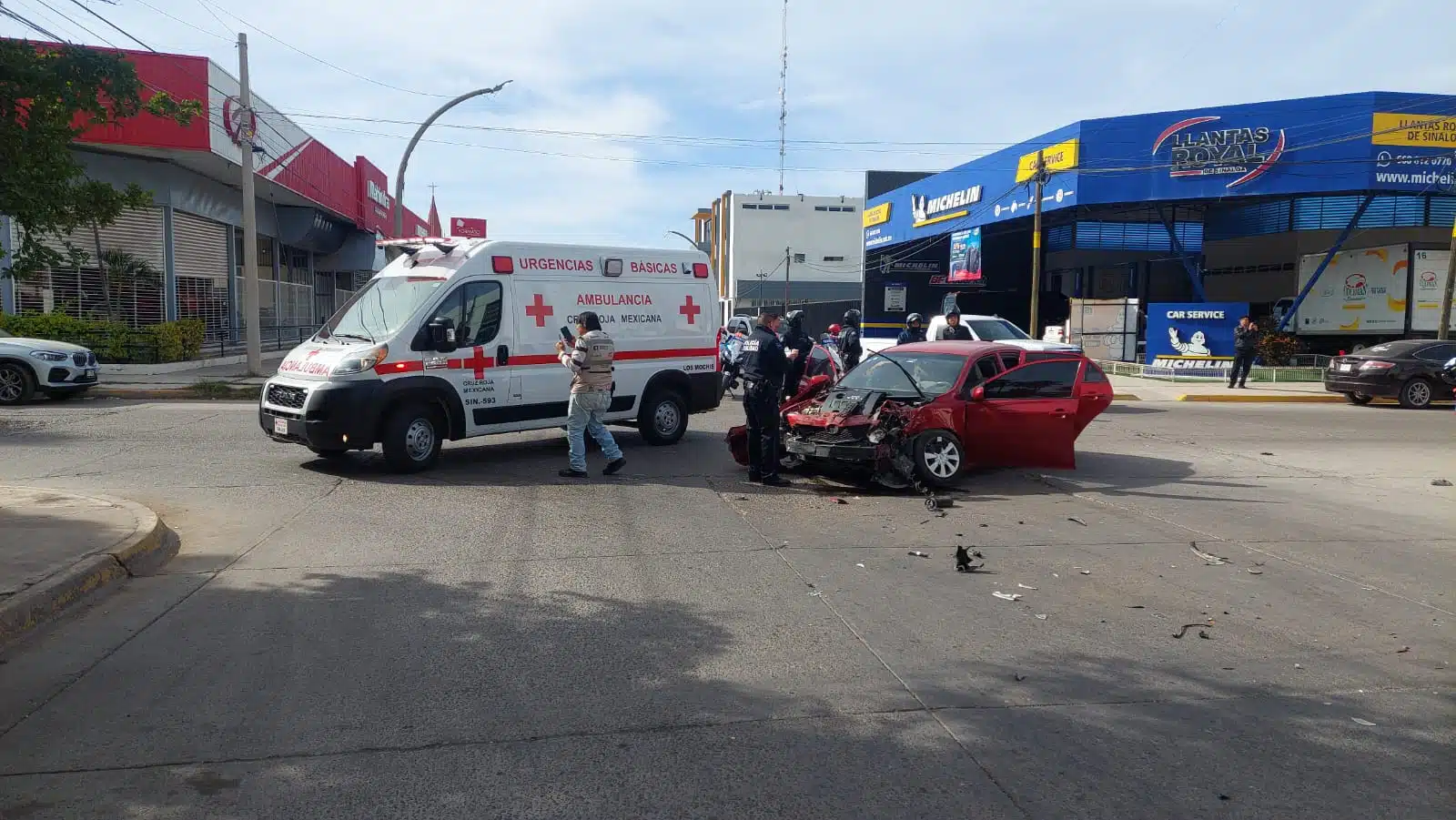 Carro chocado del frente tras un fuerte accidente con las puertas abiertas y una ambulancia de la Cruz Roja en Los Mochis