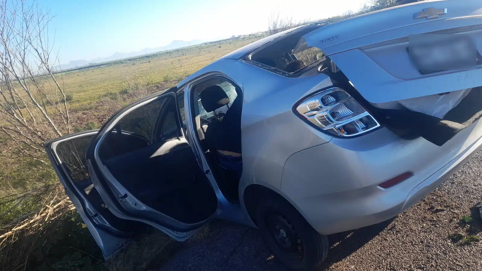 Un carro inclinado sobre su parte delantera, con las puertas y la cajuela abierta tras un accidente en El Fuerte