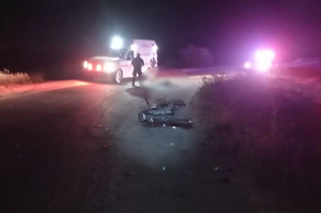 Motocicleta tirada en la carretera, a poca distancia un hombre tirado y una ambulancia