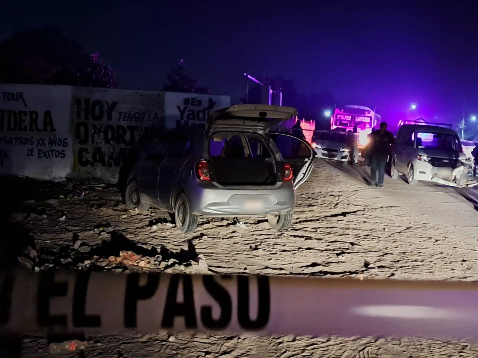 Carro abandonado con impactos de bala y cinta amarilla acordonando el lugar