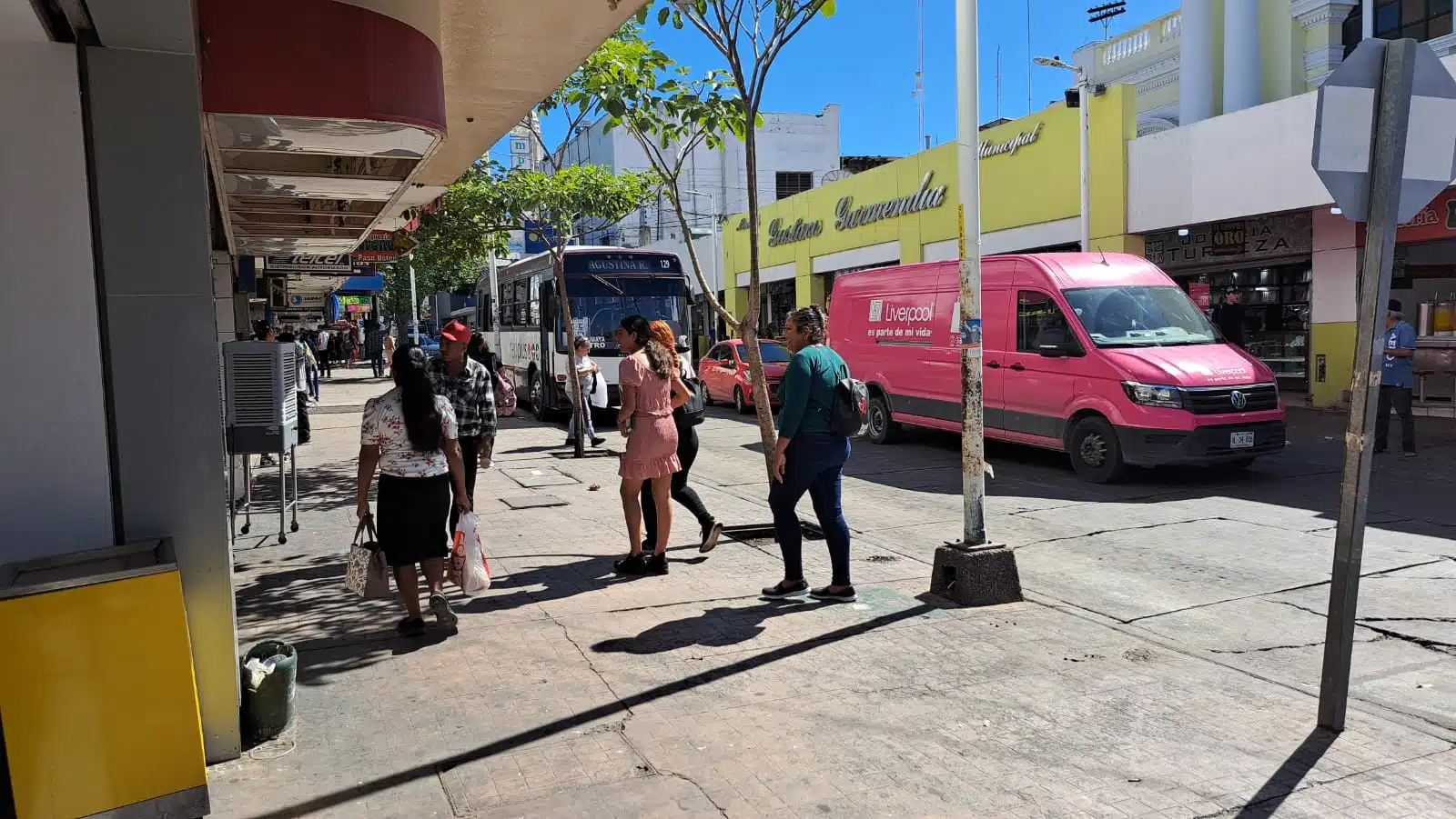 Personas caminando por el centro y camiones urbanos en una parada en Culiacán