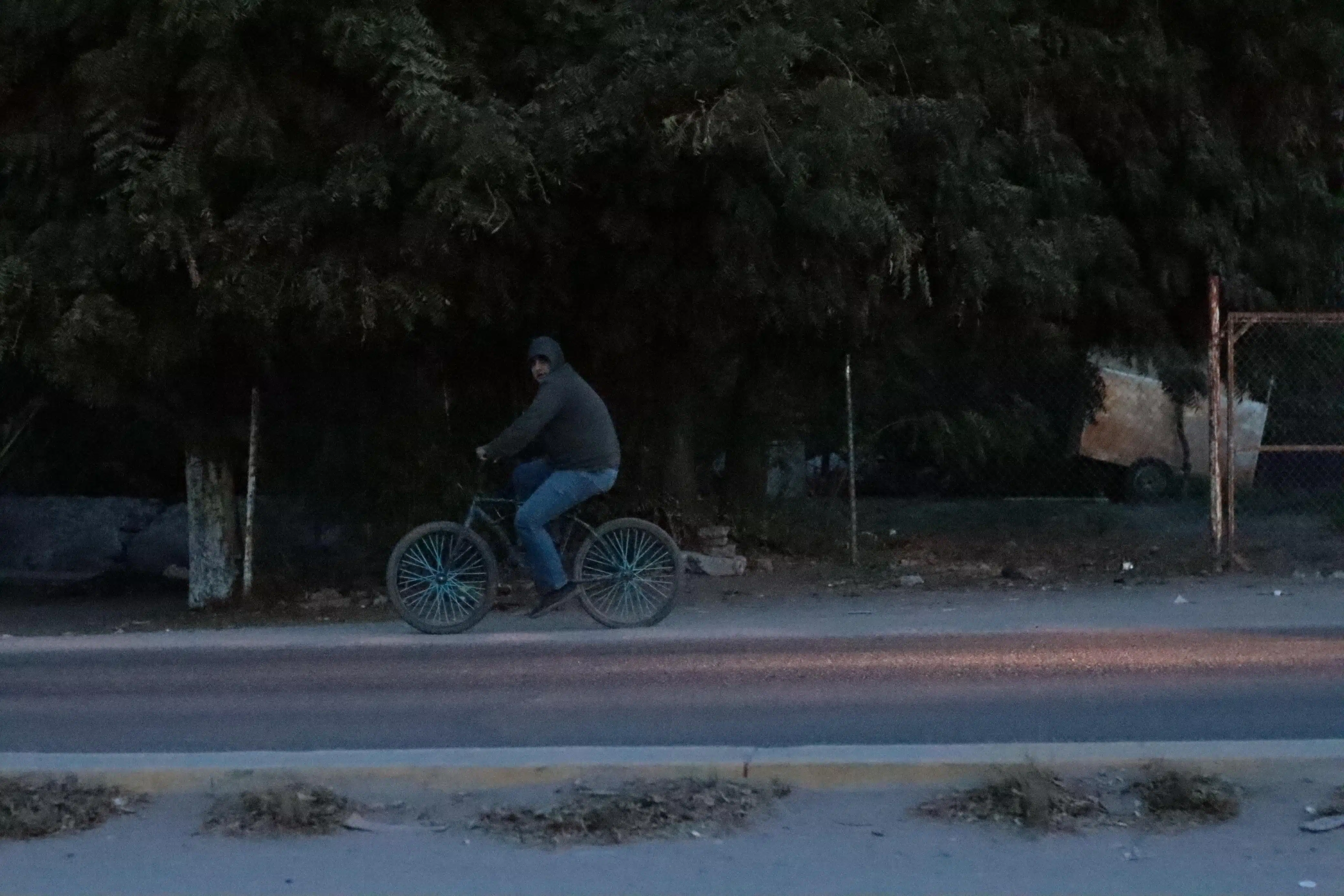 Una persona en bicicleta bien abrigada por el intenso frío en Sinaloa