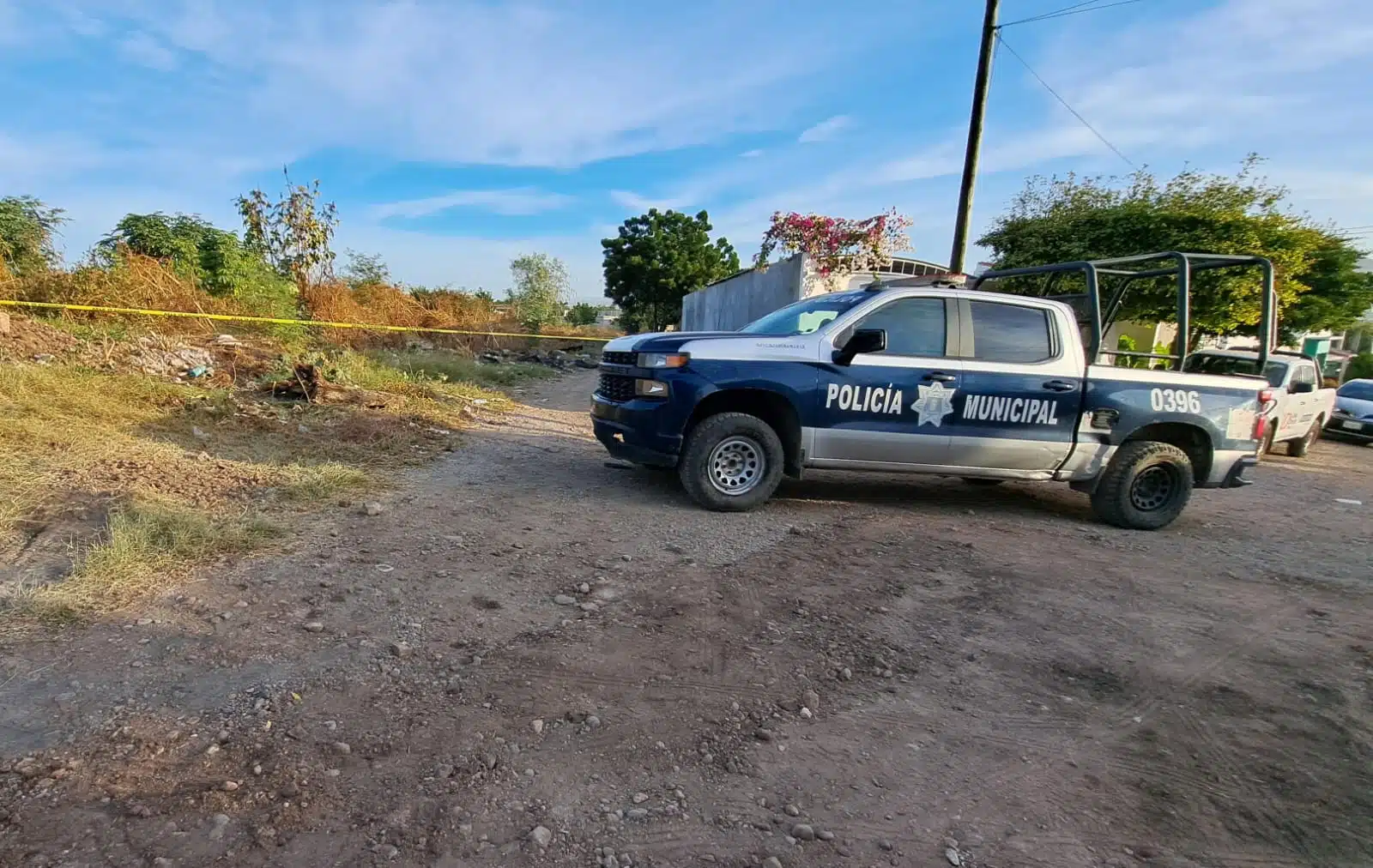 Camioneta de la Policía Municipal y cinta amarilla delimitando el área donde se encontró el cuerpo de un hombre asesinado en Culiacán