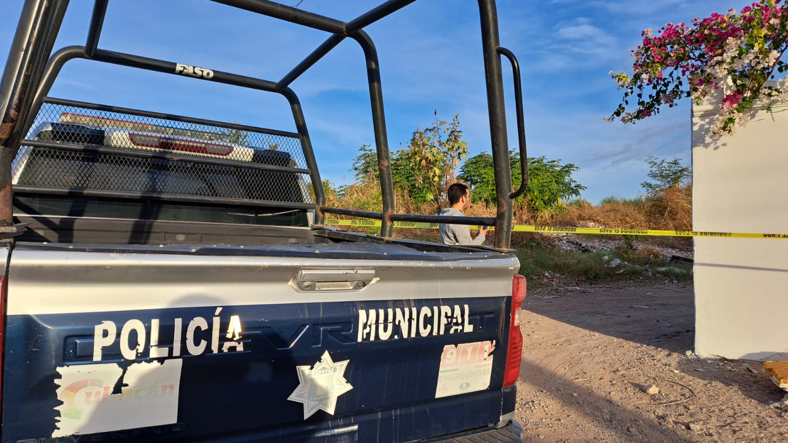 Camioneta de la Policía Municipal y cinta amarilla delimitando el área donde se encontró el cuerpo de un hombre asesinado en Culiacán
