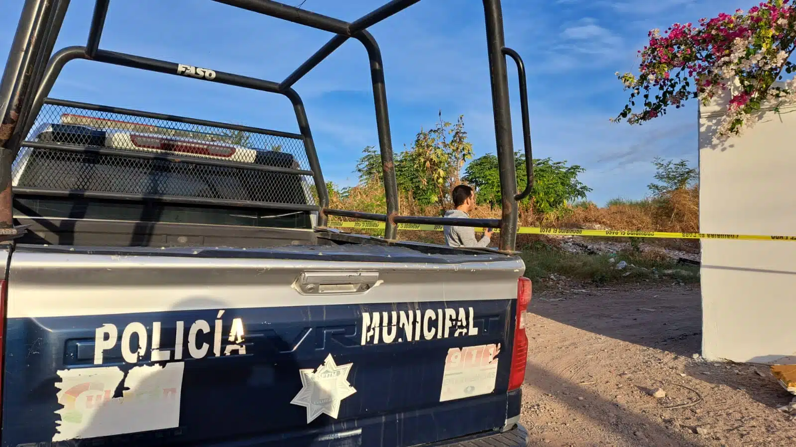 Camioneta de la Policía Municipal y cinta amarilla delimitando el área donde se encontró el cuerpo de un hombre asesinado en Culiacán