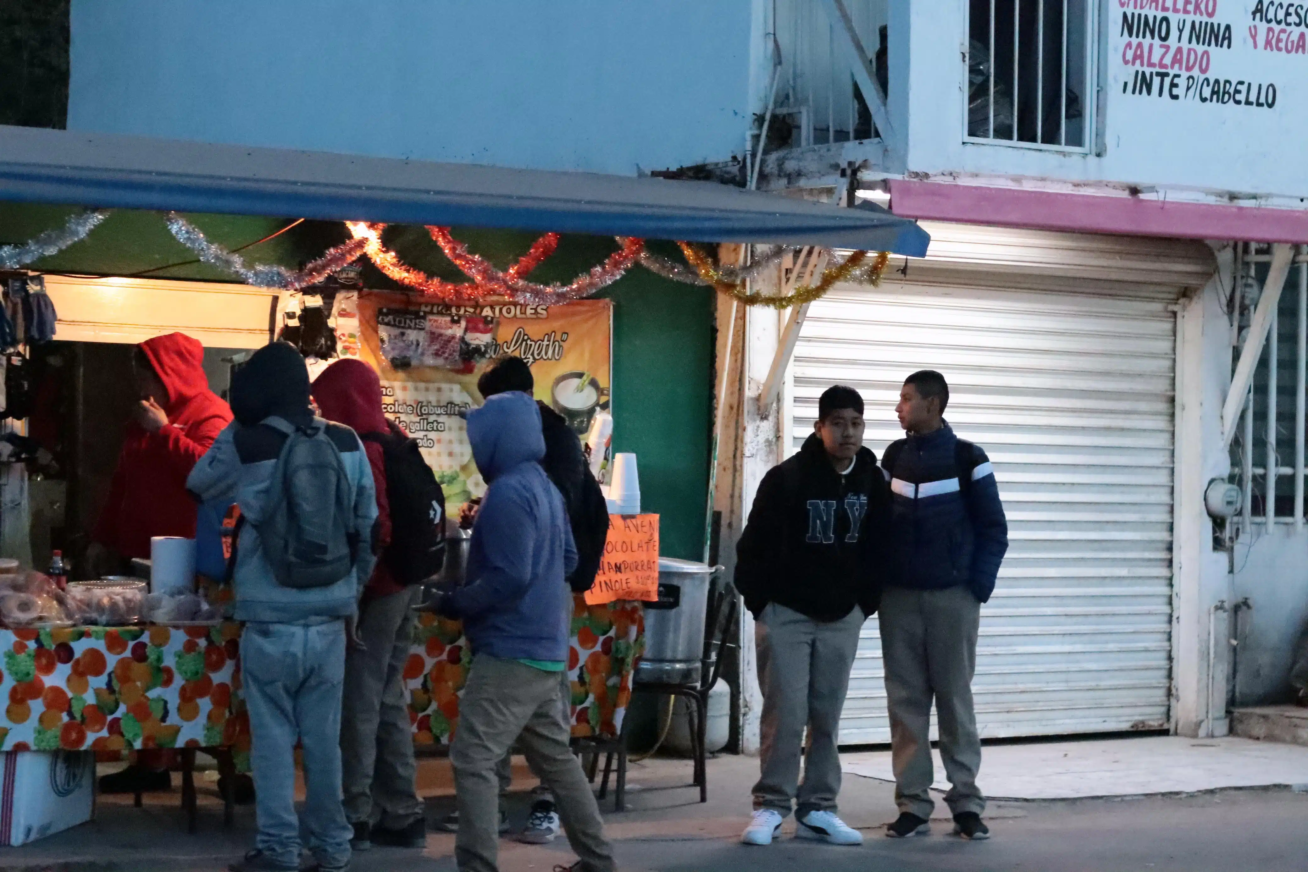 Jovenes y trabajadores en medio del intenso frío en la mañana.