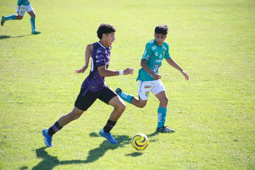 Jugador del Mazatlán FC y otro del León en la cancha de futbol tras el balón