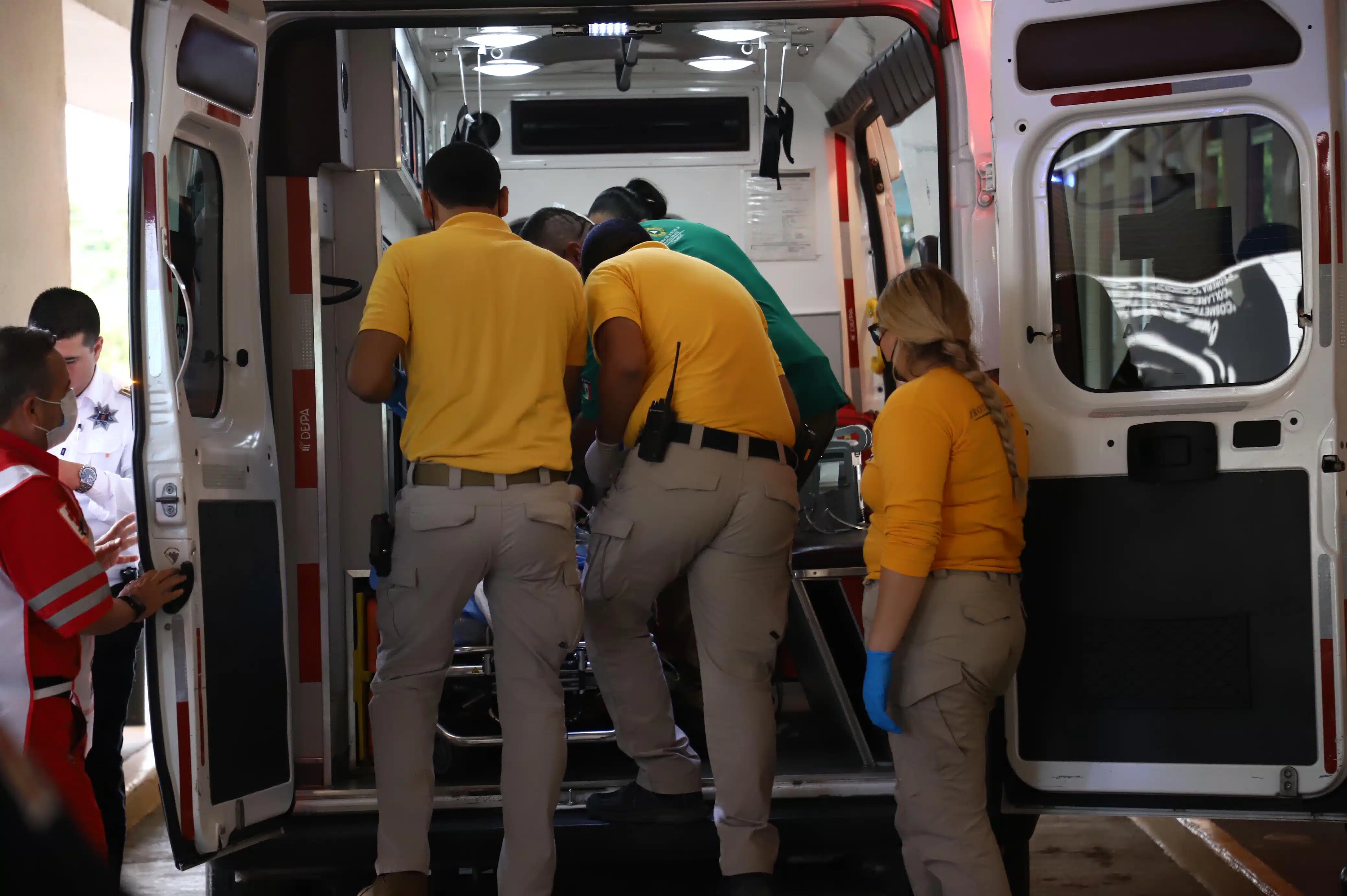 Paramédicos en ambulancia tratando de sacar a paciente afuera de un hospital