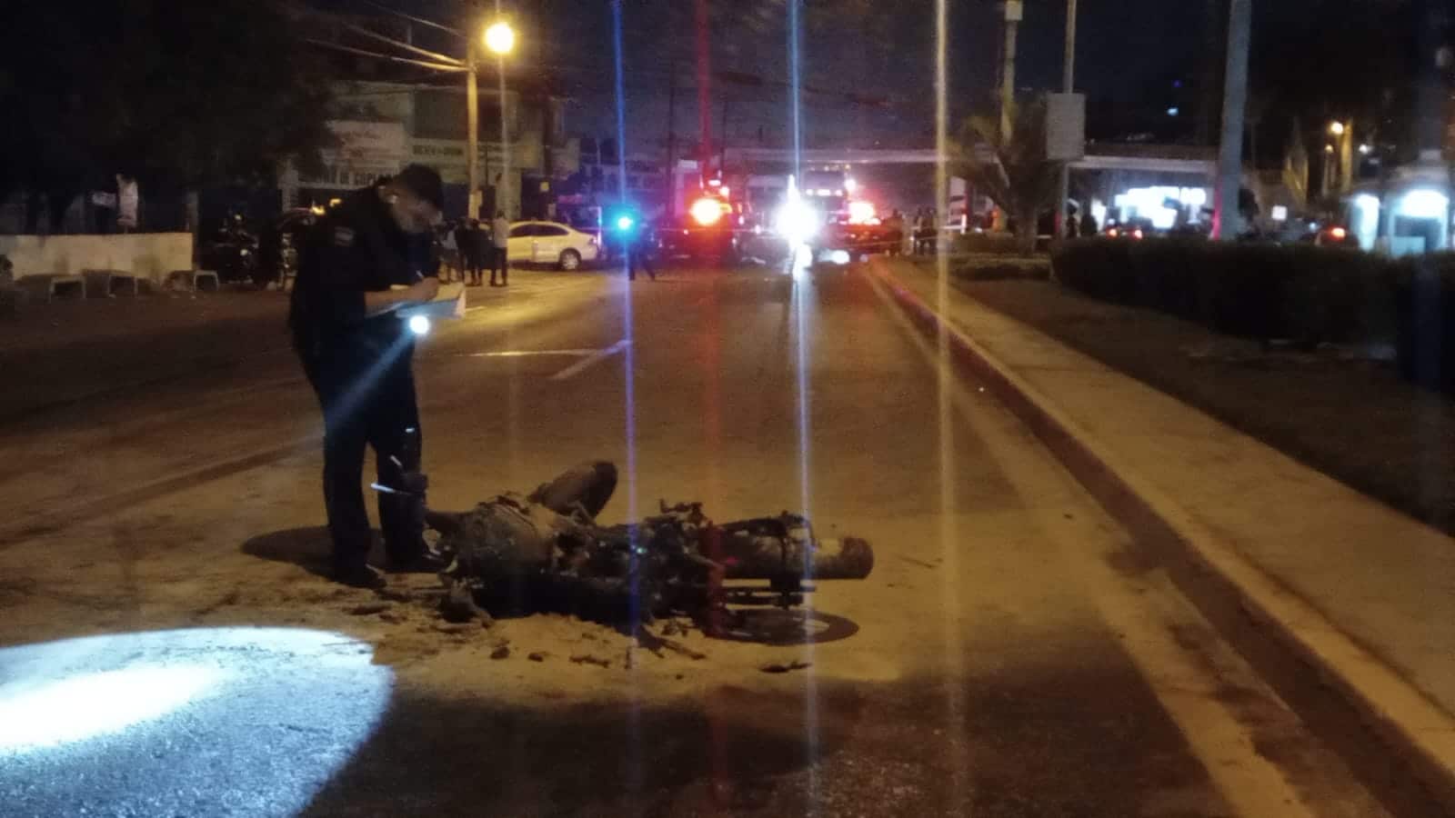 Policía de Tránsito tomando fotografía a una motocicleta tras accidente