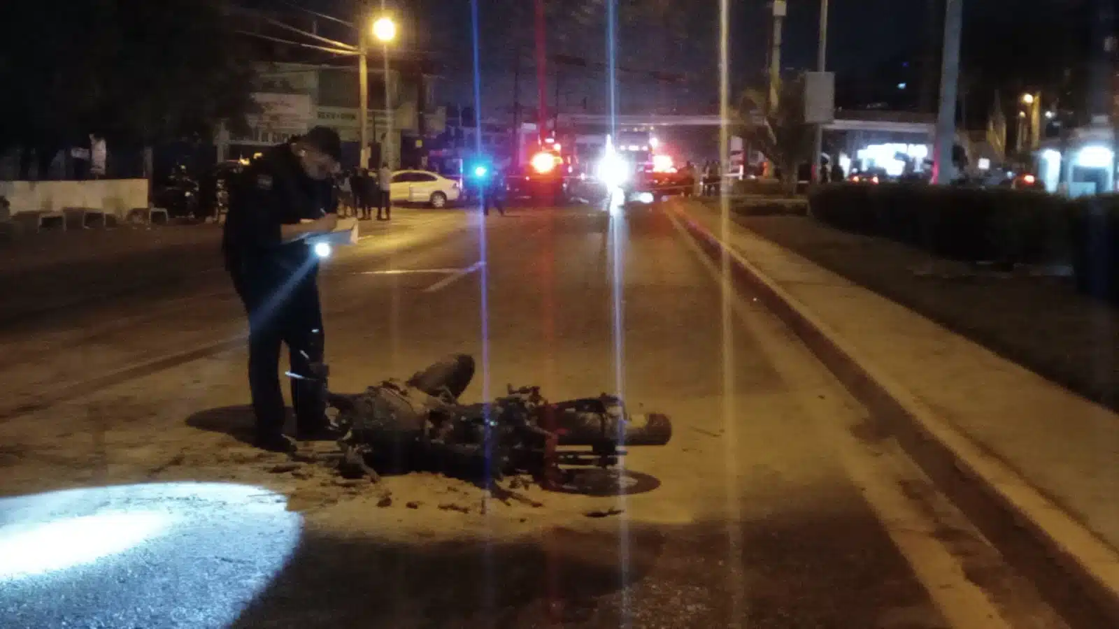 Policía de Tránsito tomando fotografía a una motocicleta tras accidente