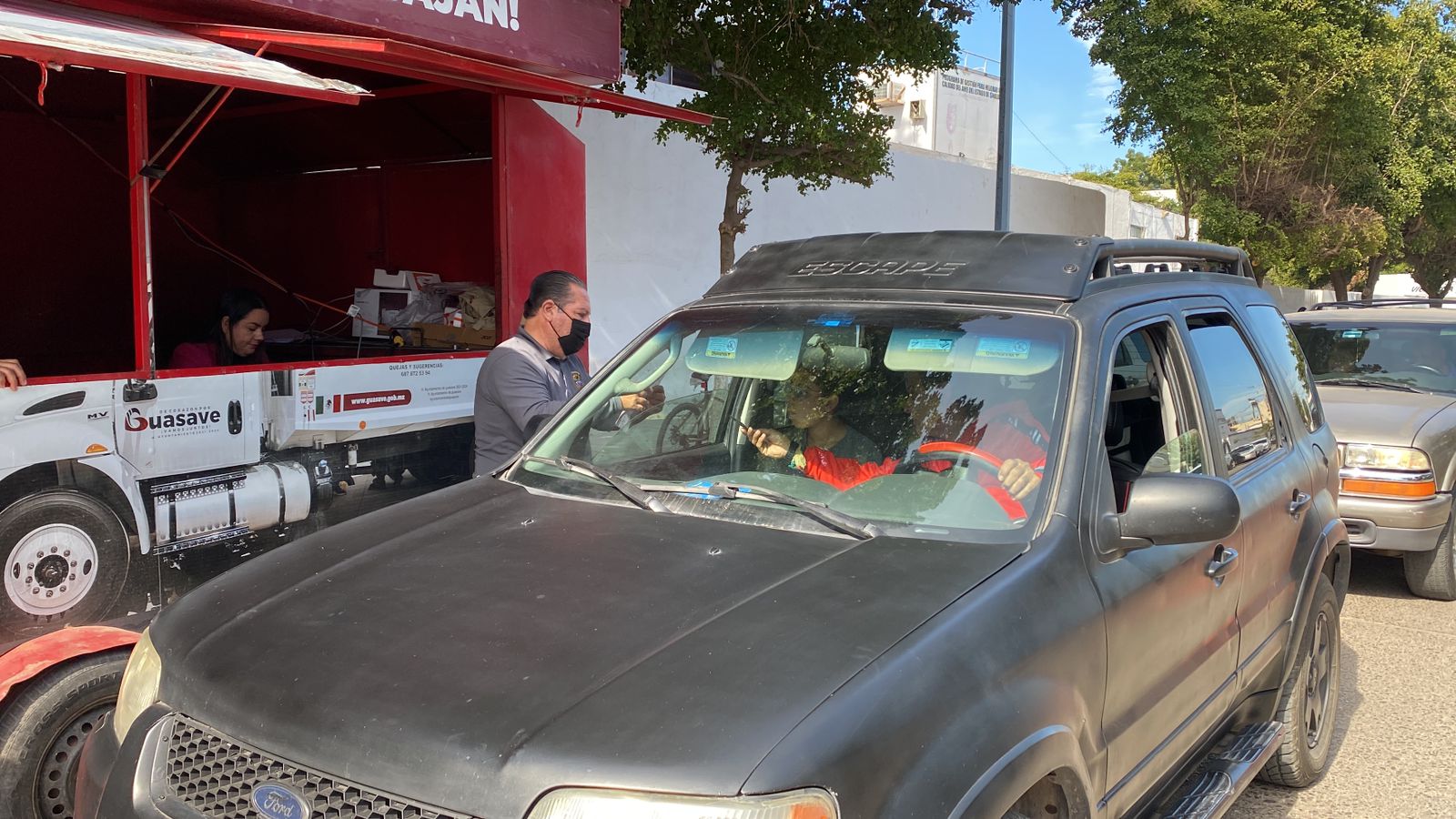 Un carro y una persona en un módulo móvil de pago para le predial de Guasave
