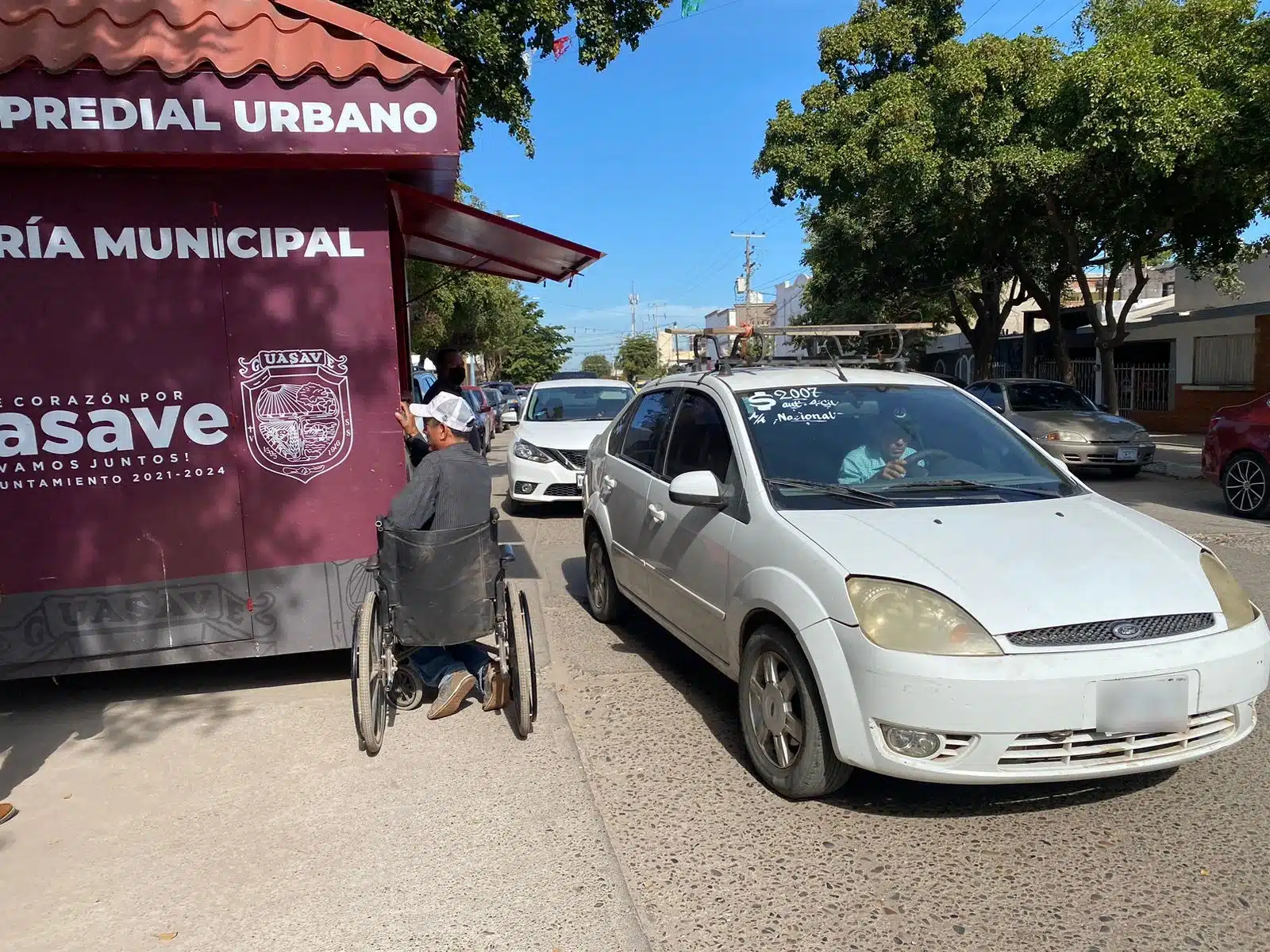 Un carro y una persona en un módulo móvil de pago para le predial de Guasave