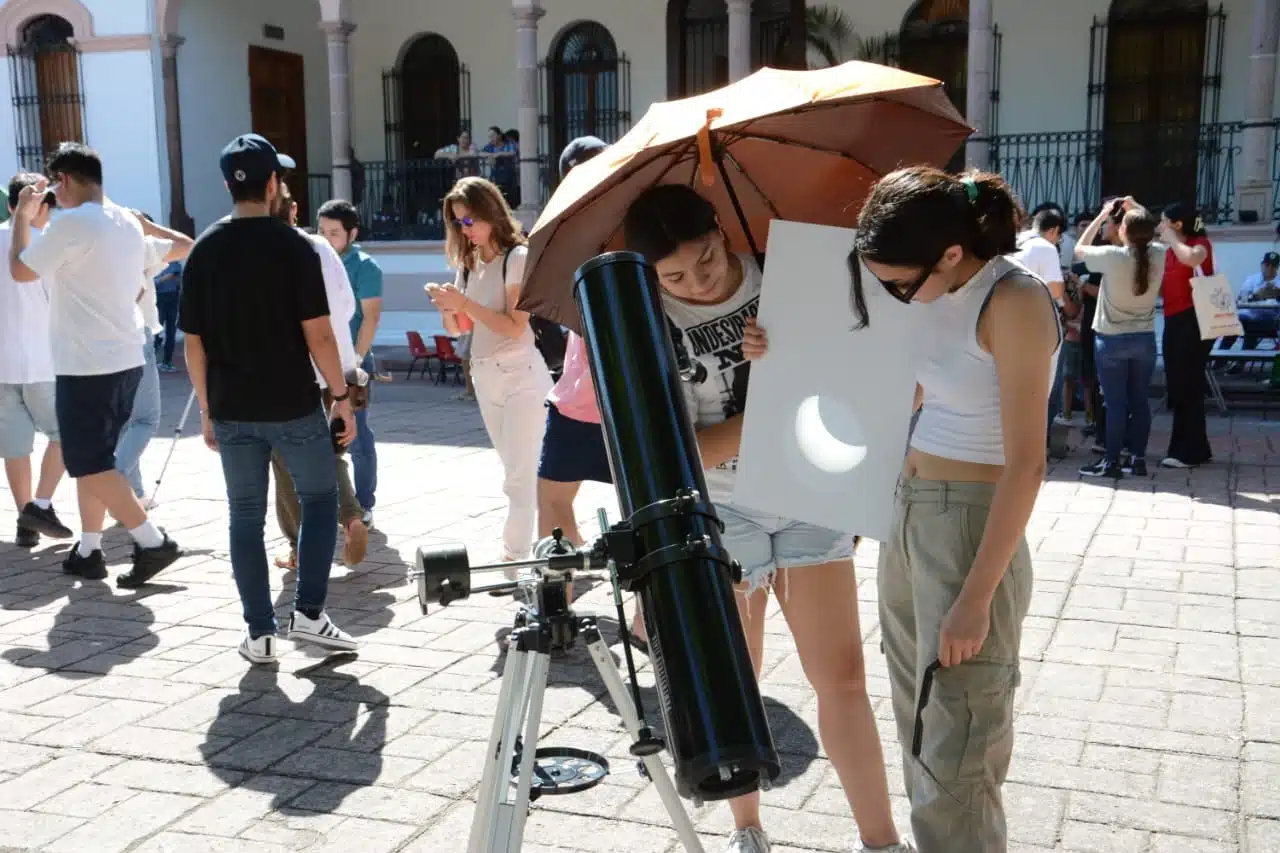 Personas reunidas para visualizar un evento astronómico a través de un telescopio