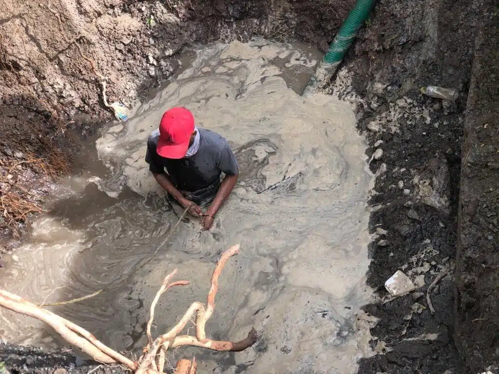 Hombre adentro de un agujero con agua por reparaciones de Jumapam