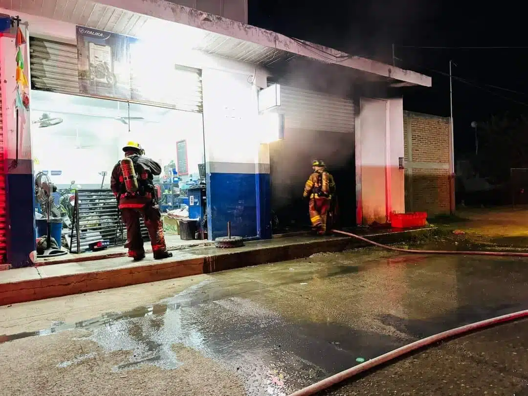 Bomberos combatiendo el incendio en la bodega de motocicletas