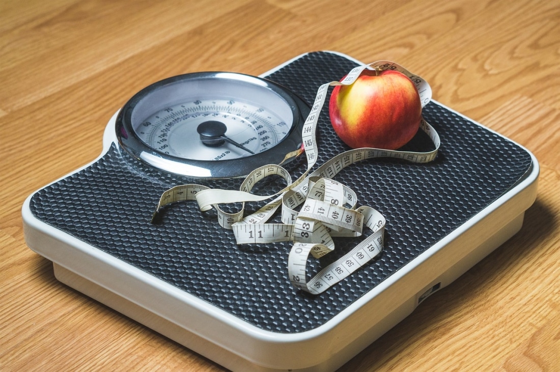 Una manzana y una cinta métrica encima de una báscula