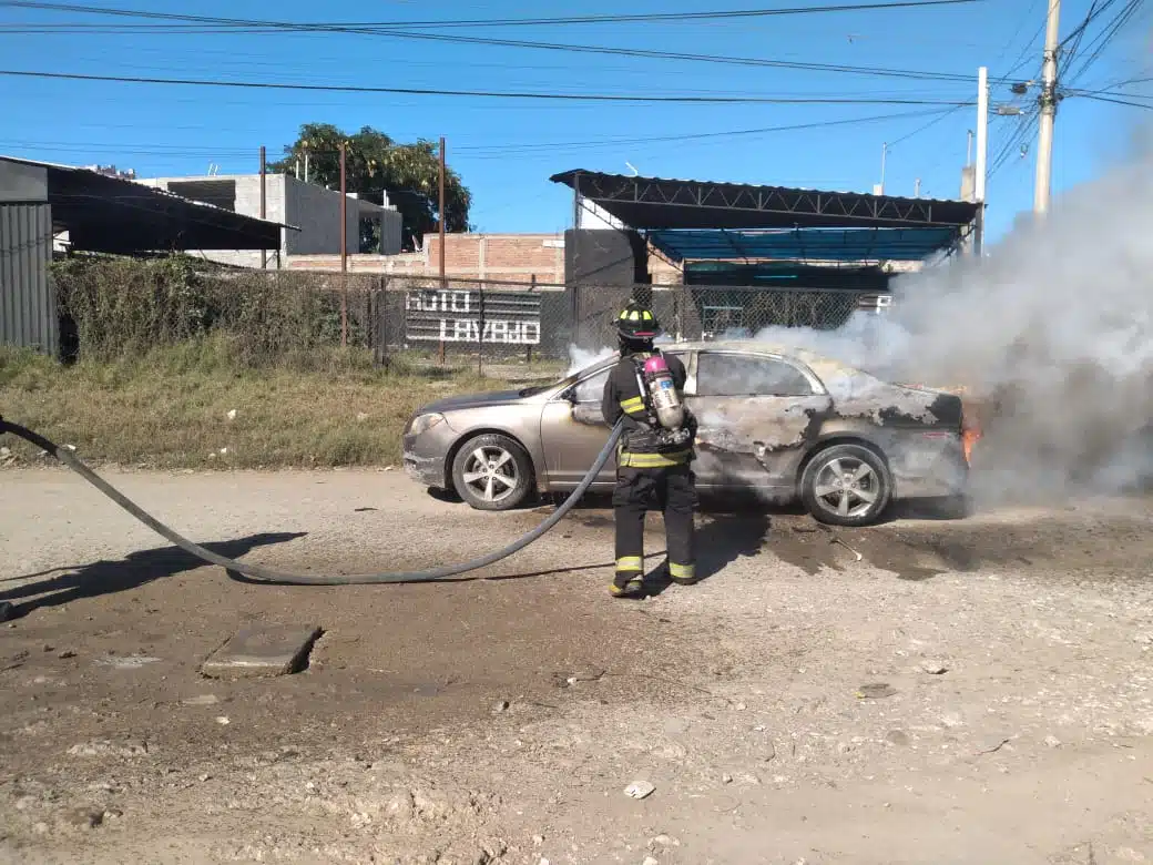 Bomberos combatiendo el incendio del vehículo hasta sofocar por completo las llamas.