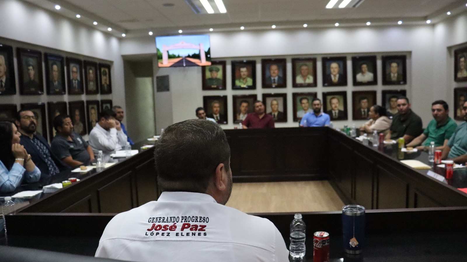 Alcalde de Badiraguato de espaldas en salón de cabildo acompañado de regidores
