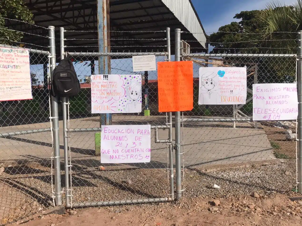 Pancartas pegadas en la puerta de una escuela donde piden maestros