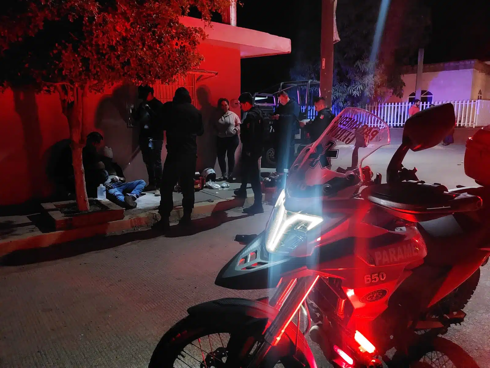 Motocicleta y elementos de la Policía Municipal de Culiacán, rescatistas del grupo Gerum dando los primeros auxilios a Manuel, joven que fue herido en la cabeza